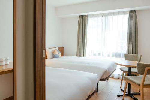 京都OMO5 Kyoto Sanjo by Hoshino Resorts的酒店客房设有两张床和一张桌子。
