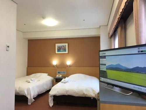 酒田市Hotel Alpha-One Sakata的酒店客房设有两张床和一台平面电视。