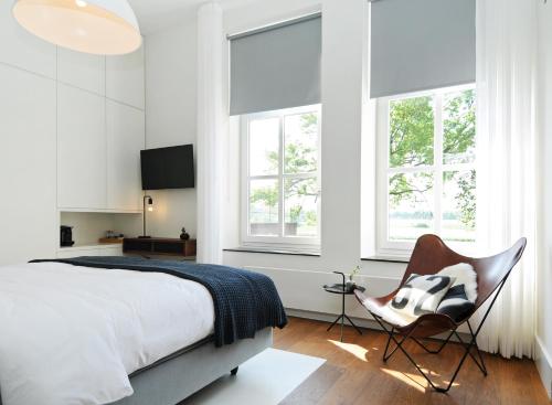凯瑟尔Het Raadhuys - design B&B的一间卧室配有一张床、一把椅子和窗户。