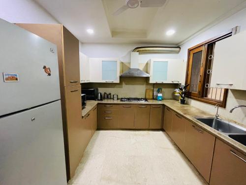 新德里Fortune Home Service Apartment 4Bhk,J-191 Saket的厨房配有棕色橱柜和白色冰箱