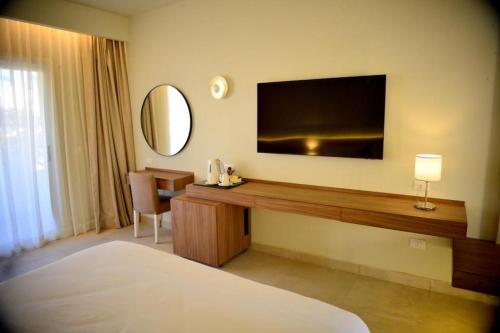 沙姆沙伊赫Reef Oasis Beach Aqua Park Resort的酒店客房设有一张桌子,墙上配有电视