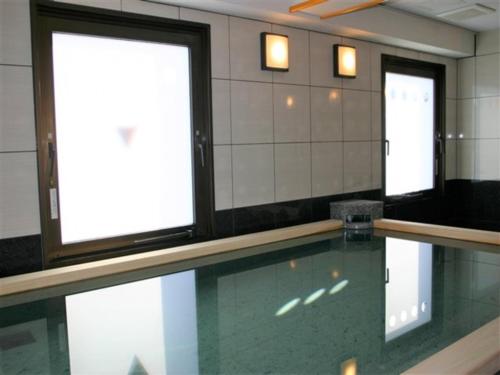 津山市Hotel Alpha-One Tsuyama的一个带两个窗户的房间的游泳池