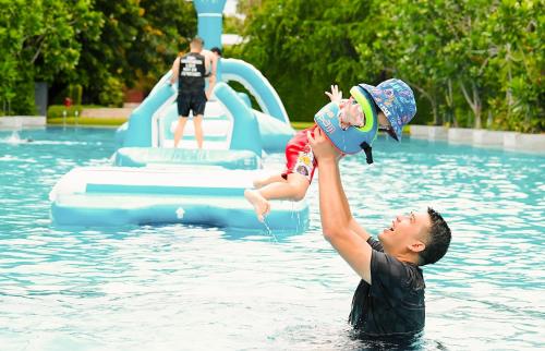 七岩SO/ Sofitel Hua Hin的把婴儿抱在游泳池里的男人