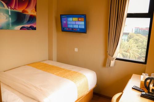 雅加达Grand Ametis Hotel Jakarta的卧室配有一张床,墙上配有电视。