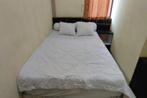 查亚普拉OYO 93479 Hotel Jaguar Sentani的一张位于小客房内的床铺,配有白色棉被