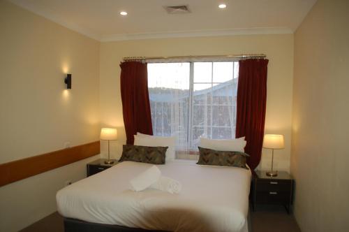 奥尔伯里Meramie Motor Inn的一间卧室配有床和红色窗帘的窗户