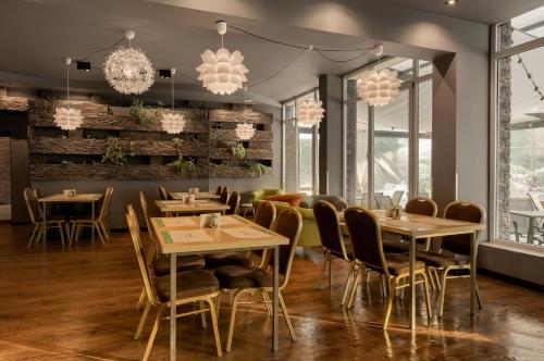 什切青Płonia Resort的餐厅设有桌椅和吊灯。