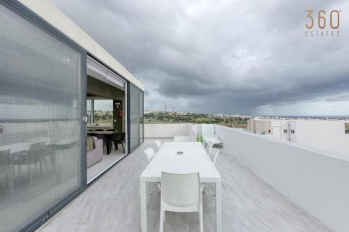 San ĠwannLUX Duplex Penthouse w/ Expansive Rooftop Terrace by 360 Estates的大楼屋顶上的白色桌子和椅子