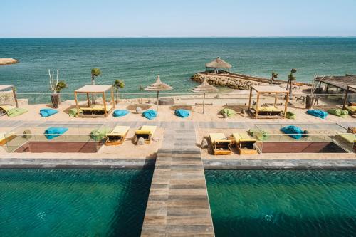达赫拉Bavaro Beach Dakhla的毗邻大海的带椅子和遮阳伞的游泳池