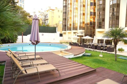 里斯本Legendary Lisboa Suites的一个带椅子和遮阳伞的庭院和一个游泳池