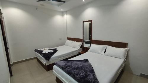 乌贾因Shree Govindam Guest House的小型客房的两张床,配有镜子