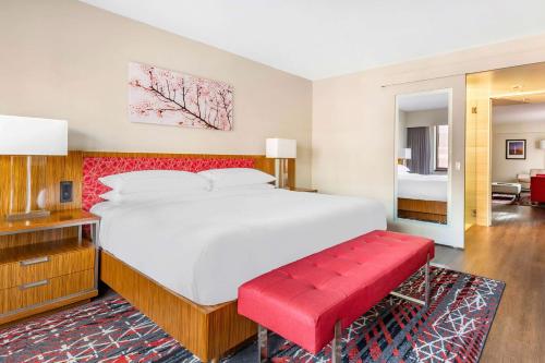 华盛顿Hilton Club The District Washington DC的一间卧室设有一张大床和一张红色长凳