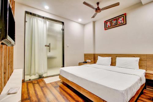 博帕尔FabHotel Manjeet的一间卧室设有一张床和一个玻璃淋浴间