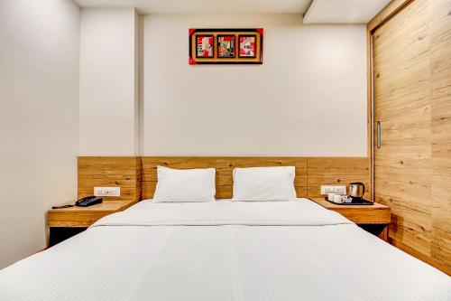博帕尔FabHotel Manjeet的卧室配有一张白色大床和墙上的时钟