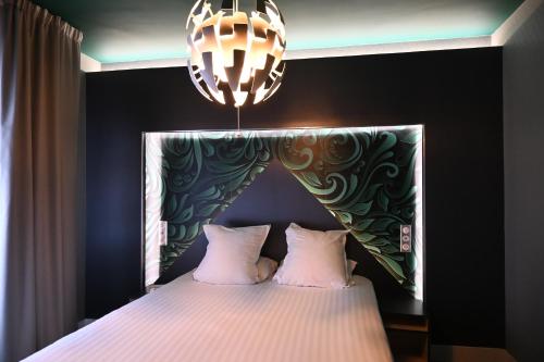 敦刻尔克LOGIS Hôtel Borel的一间卧室配有一张床和一个吊灯