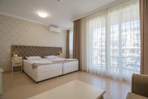 阳光海滩Rena Hotel - All Inclusive的一间卧室设有一张床和一个大窗户