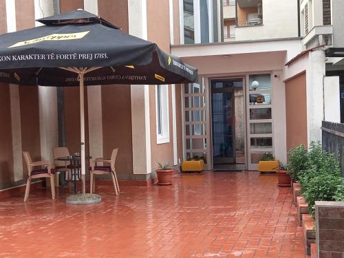 佩奇Hotel Peja的庭院配有遮阳伞和桌椅。