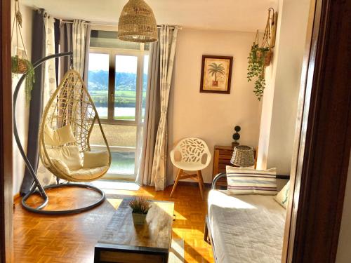 里瓦德塞利亚Apartamento con vistas espectaculares al rio Sella的客厅的窗户前设有秋千