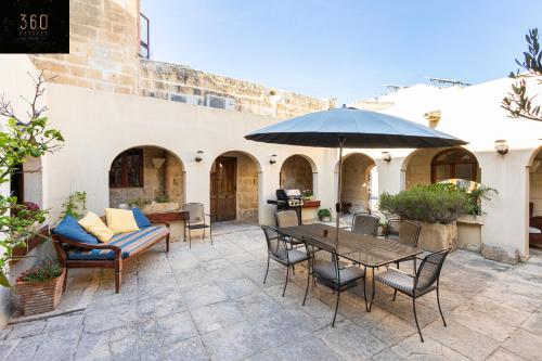 ŻebbuġA stunning, townhouse with magnificent pool area by 360 Estates的庭院配有桌椅和遮阳伞。