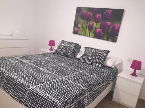 特鲁埃尔Apartamento Centro Historico Teruel的一间卧室配有一张黑色和白色的床,配有紫色郁金香