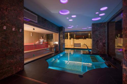里乔内The Promenade Luxury Wellness Hotel的浴室设有游泳池,浴缸内有一人