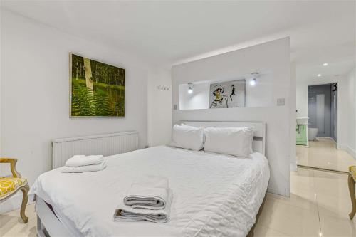 伦敦Earls Court Spacious Apartment的白色卧室配有带毛巾的大型白色床