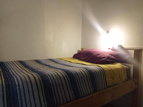 圣地亚哥Origenes的一张带条纹毯子和墙上灯的床