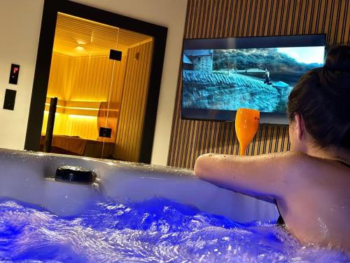 卡托维兹Jacuzzi Loft & Sauna Sanctuary的一个人在浴缸里,在房间里配有电视