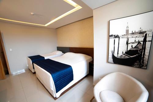 瓜拉普阿瓦Adria Premium Hotel的酒店客房,配有一张床和两把椅子