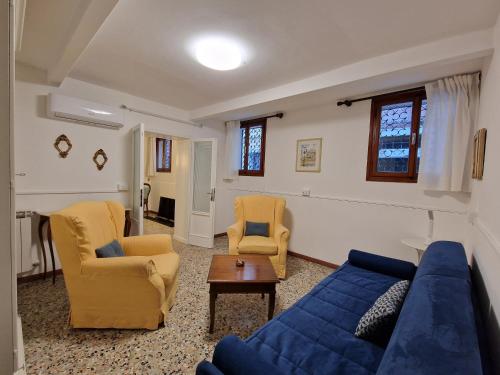 威尼斯Veneziacentopercento Apartments & Rooms的客厅配有蓝色的沙发和两把椅子