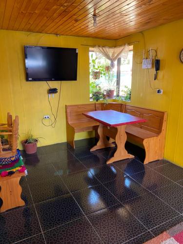 奇廉Casa Mía Blue 2的一间设有桌子的用餐室和一台黄色墙壁上的电视