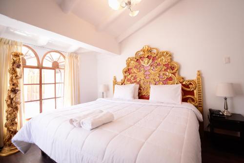 库斯科Hotel Monasterio del Inka的一间卧室配有一张白色大床和金色床头板