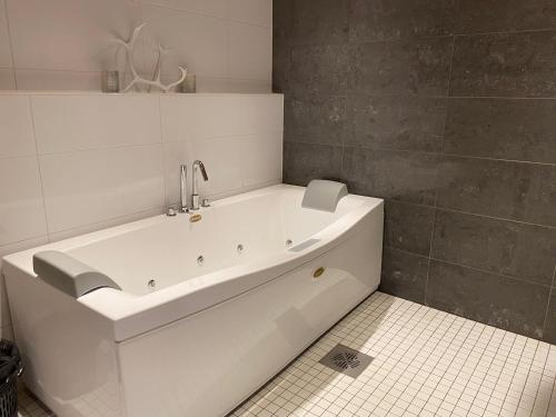 罗瓦涅米Villa Harmony的浴室铺有瓷砖地板,配有白色浴缸。