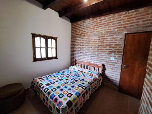 蒂尔卡拉Kurpachana cómodos departamentos a 3 cuadras de la plaza.的一间卧室设有一张床和砖墙