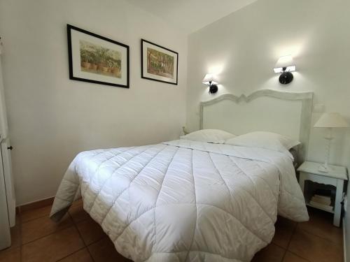 马莱莫尔LOCATION 4 personnes GOLF DE PONT ROYAL EN PROVENCE的卧室配有一张白色床,墙上挂有两张照片