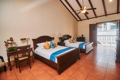 格拉纳达Hotel Plaza Colon - Granada Nicaragua的一间卧室配有两张床、一张桌子和一张书桌