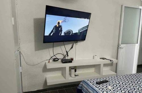 埃斯孔迪多港TMX HOSTAL的挂在床上方墙上的平面电视