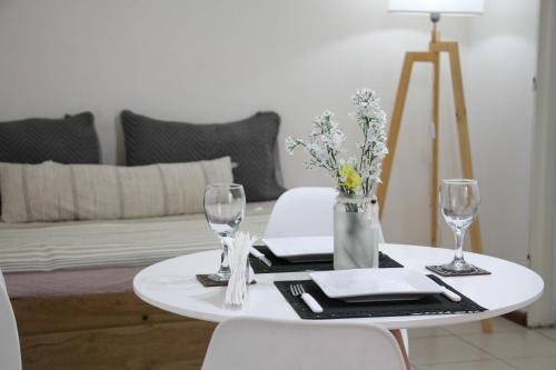 门多萨La Quinta departamento的一张带两把椅子的白色桌子和一张带酒杯的桌子