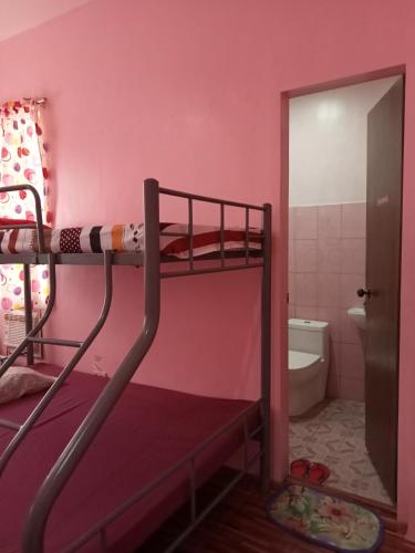 董索Josephine's Home Donsol Sorsogon的粉红色客房内的双层床,设有浴室