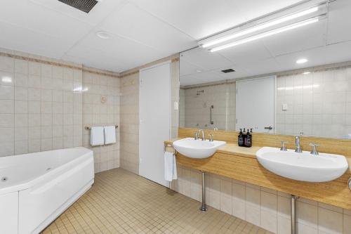 阿德莱德Comfort Hotel Adelaide Meridien的浴室设有2个水槽、浴缸和镜子