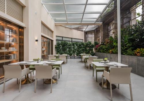 深圳格兰云天·阅酒店(深圳中心公园店)的一间设有桌椅的餐厅,种植了植物