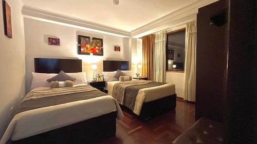 库斯科Allincay Cusco Apart Hotel的酒店客房设有两张床和窗户。