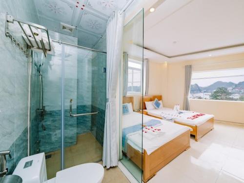 吉婆岛Lang Chai Hotel Cat Ba的浴室设有两张床和玻璃淋浴间。
