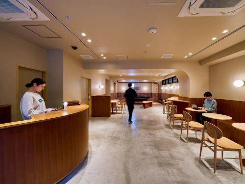 东京Hotel Plus Hostel TOKYO ASAKUSA 2的站在餐厅柜台的男女