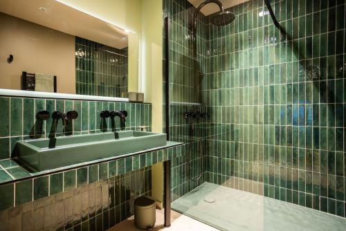 阿让Serra Boutique Hôtel的绿色瓷砖浴室设有水槽和淋浴