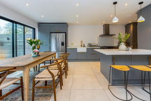 特威克纳姆Stunning 5BR Home, SW London, 5 min Twickenham St的厨房配有长木桌子和椅子
