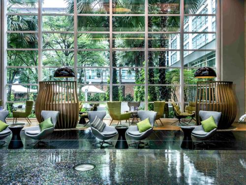 曼谷曼谷铂尔曼皇权酒店的大堂设有桌椅和大窗户。