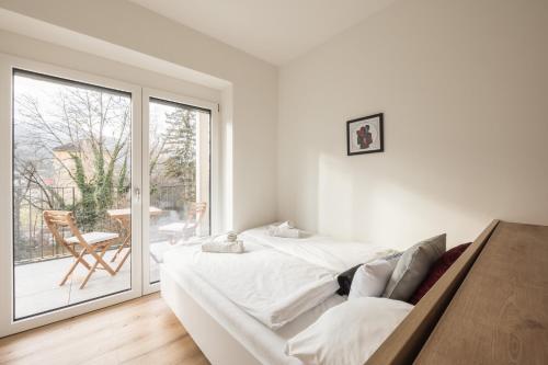 因斯布鲁克myQuartier Innsbruck City Apartments的白色卧室设有床和滑动玻璃门
