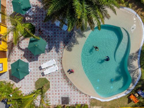 伊塔齐米林Pousada Tropicarim的享有带人员和遮阳伞的游泳池的顶部景致