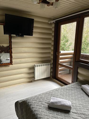 米戈韦Goral cottage in Migovo的卧室配有一张壁挂式平面电视的床。